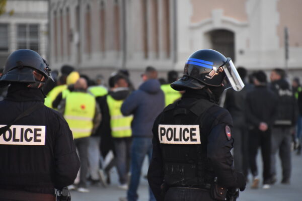 Two armed police offers standing in front of a protest