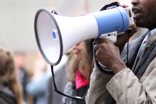 A black male protestor speaks into a megaphone
