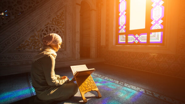 A muslim woman prays while sunlight streams in