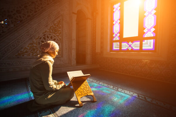 A muslim woman prays while sunlight streams in