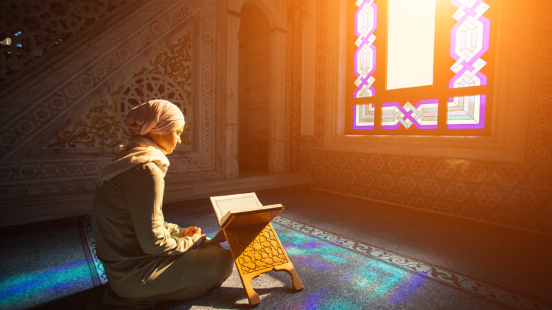 A muslim woman prays while sunlight streams in