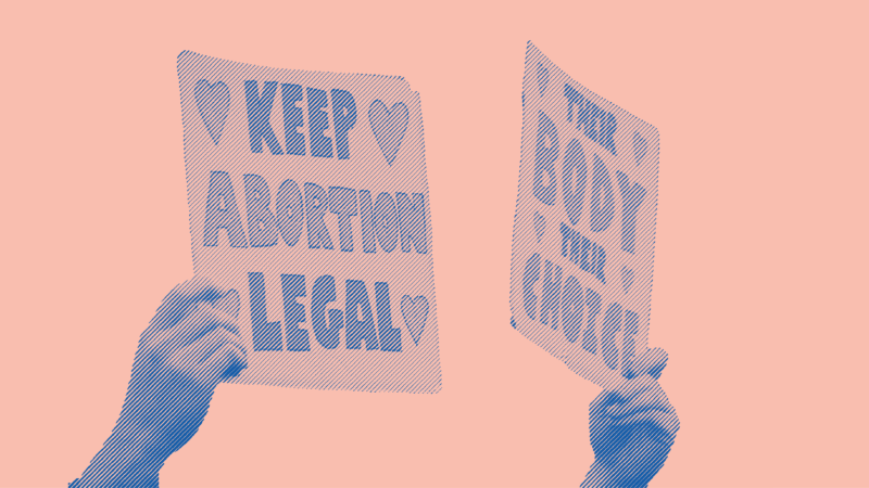 Two signs are being held at a protest. The first sign says "Keep Abortion Legal". The second sign says "Their Body Their Choice"