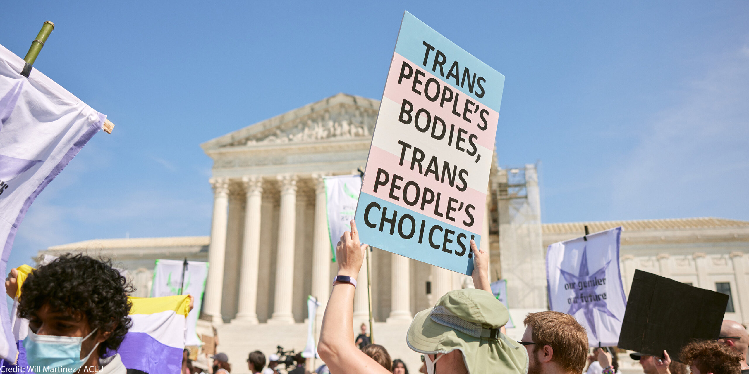 Person holding a sign in front the Supreme Court that reads Trans People's Bodies, Trans People's Choices