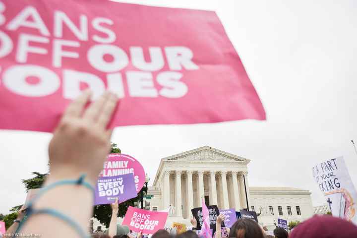 Protesters supporting abortion march in front of the Supreme Court holding signs that read "Bans off our Bodies."