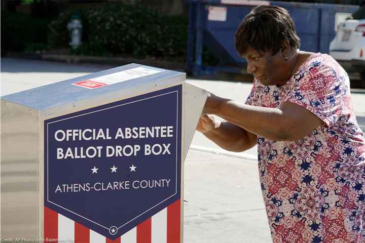 An African-American woman dropping their ballot off during early voting in Athens, Ga.