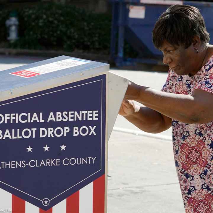An African-American woman dropping their ballot off during early voting in Athens, Ga.