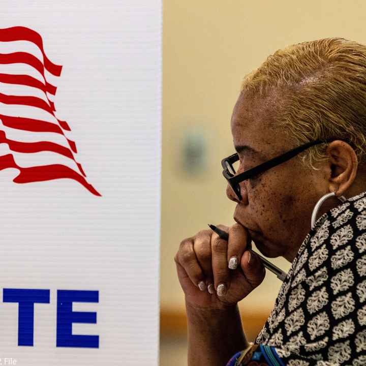 A profile view of a woman in a voting booth.